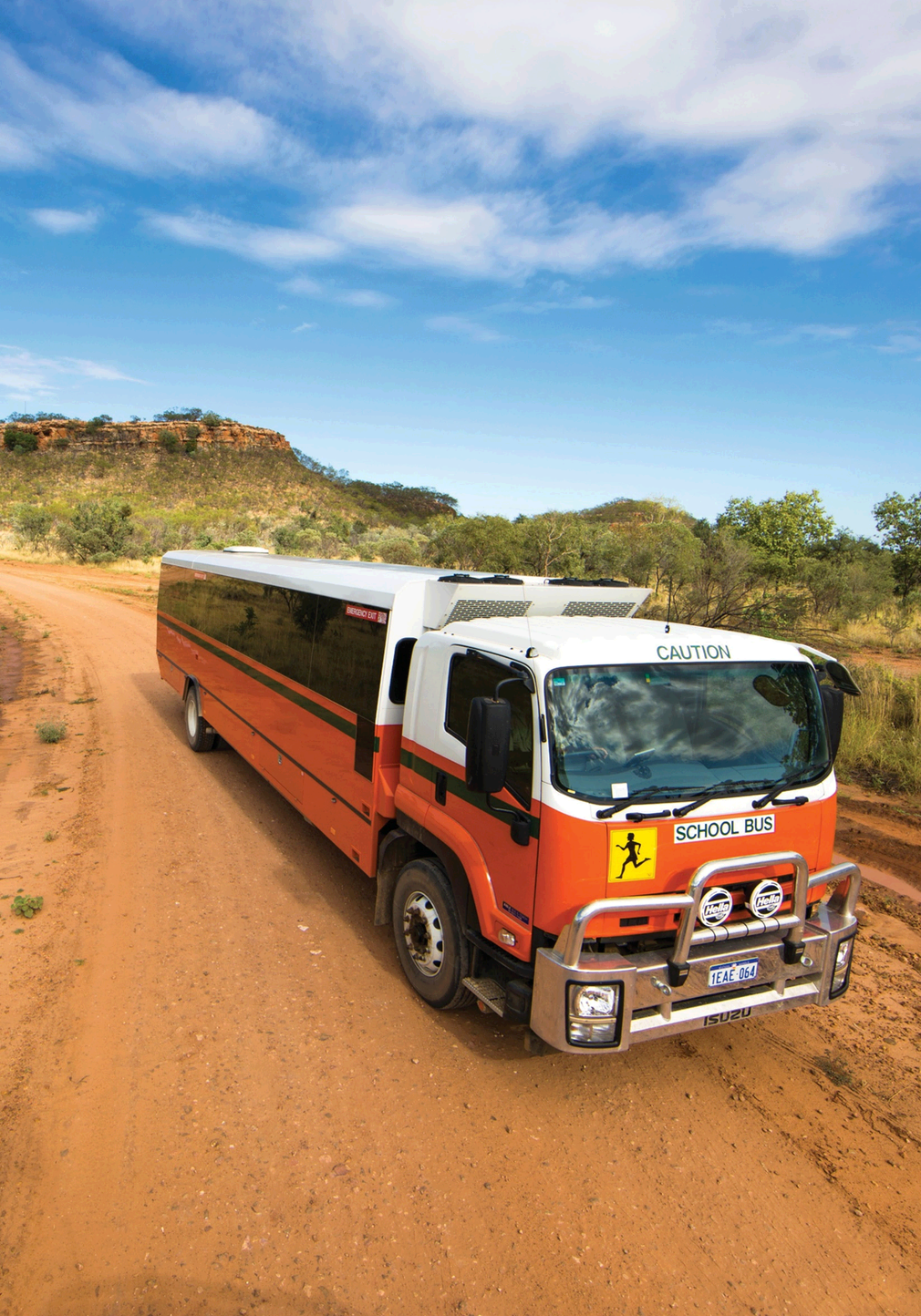 Fitzroy Crossing school bus on red Kimberley dirt road with ranges in background